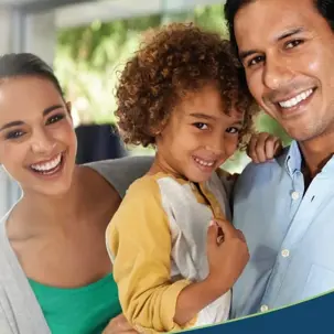 A happy, diverse family of three poses together, with a smiling woman, child, and man looking forward.