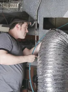 A man works on an HVAC system in a home.