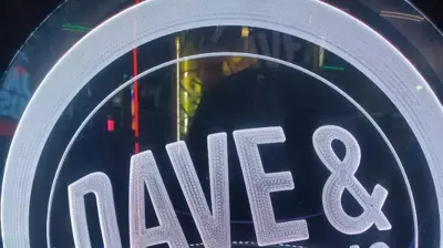 A circular, illuminated sign prominently displays the text "DAVE & BUSTER'S" in white lettering with a blue glowing border. Photo