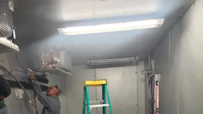 Workers installing a draught system with two kegs and connecting wiring in a refrigerated trailer. Photo