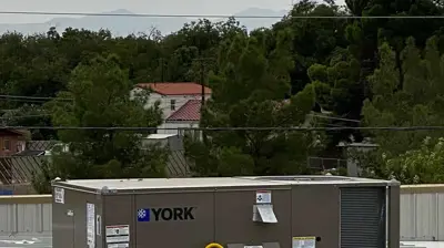 A YORK HVAC unit sits on a corrugated metal roof, with a yellow cable connected. Photo
